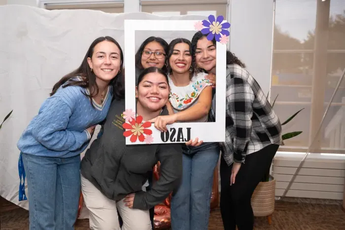 A group of students holding up a giant picture frame that says "LASO," short for "Latin American Students Organization" on it.